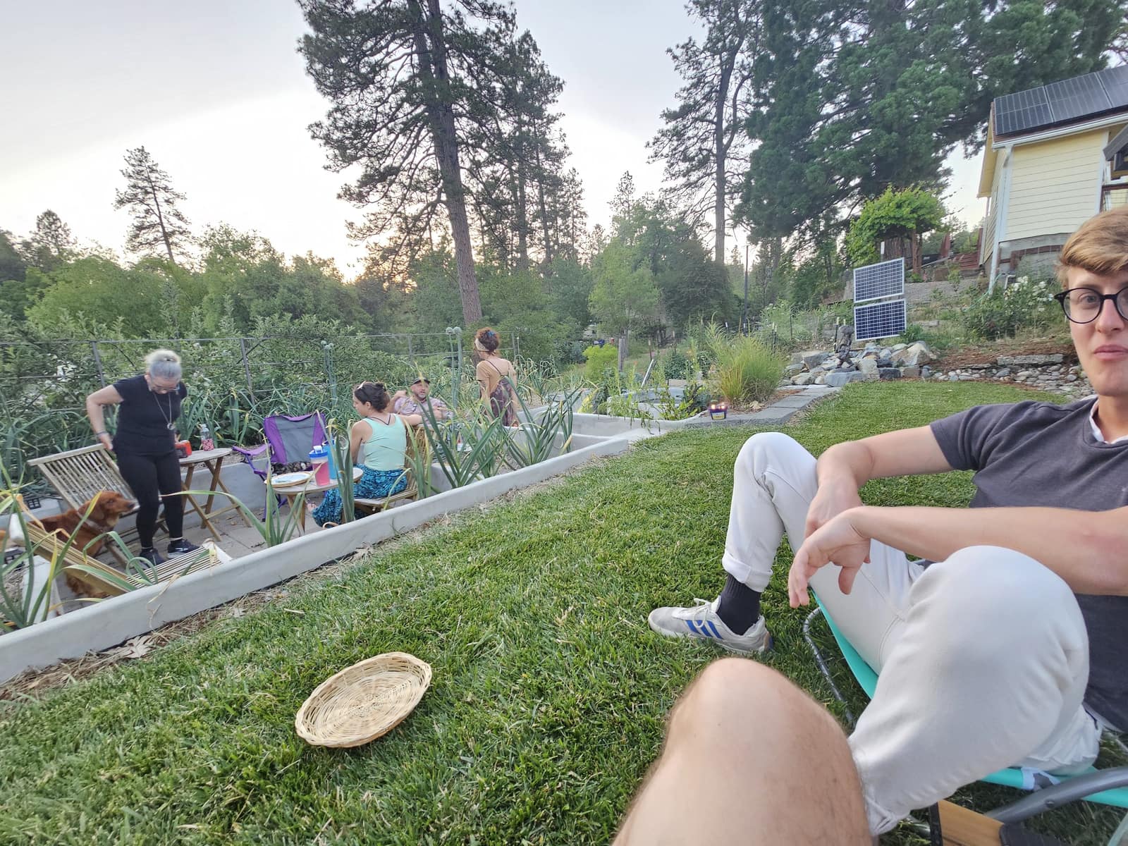 Friends gathered on the lawn at a 246 garden potluck.