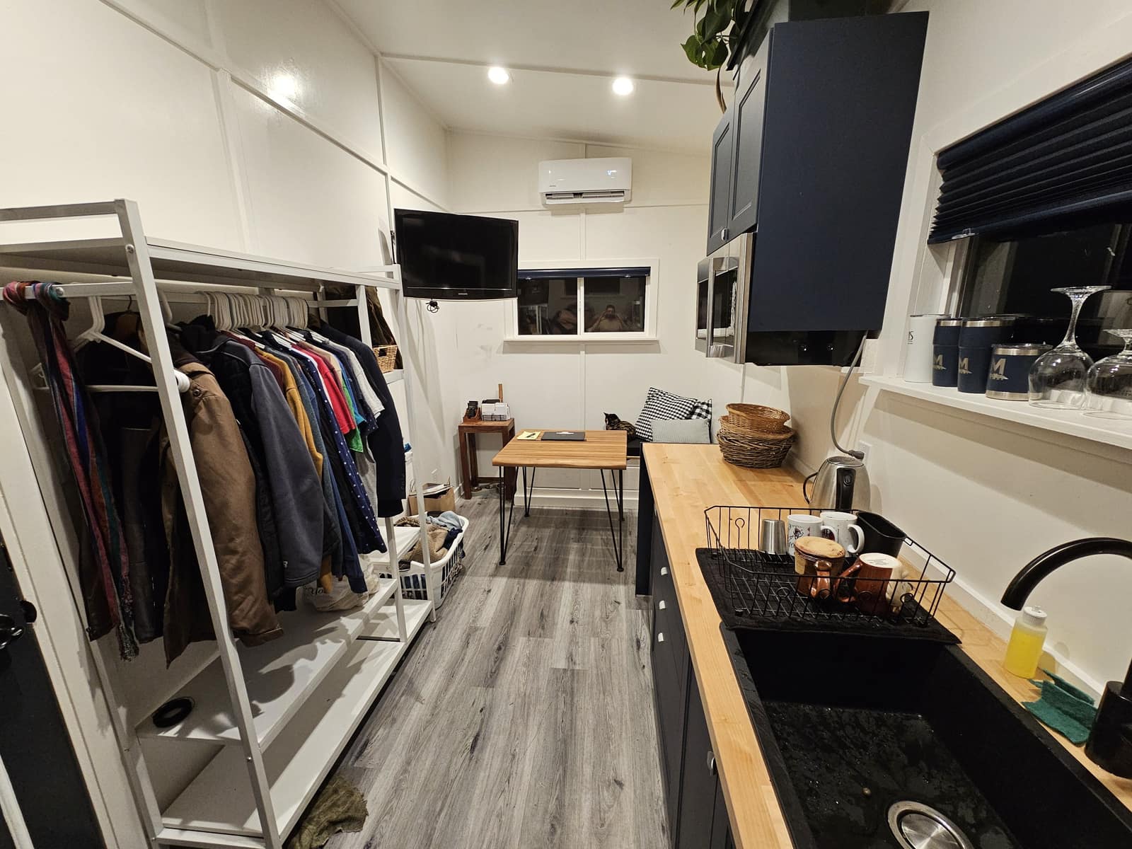 Interior of The Hideaway with a kitchen counter, a small table, and open clothes storage.