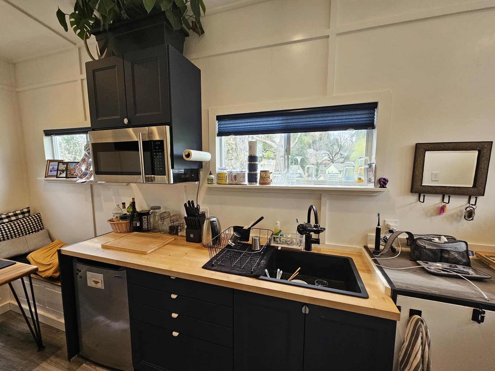 Kitchen in The Hideaway with navy cabinets, a wood counter, and a window of glassware.