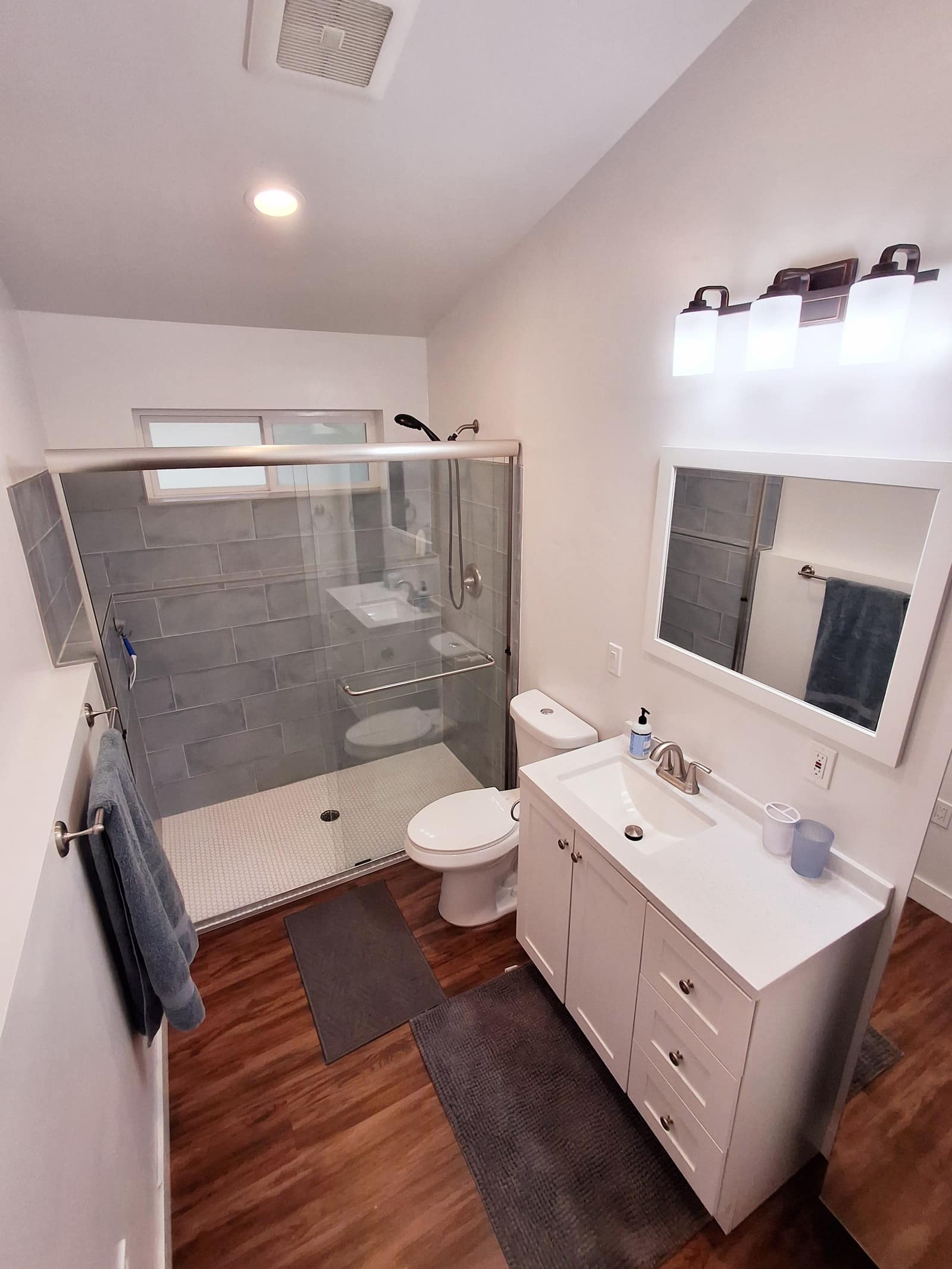 Bathroom in The Nest with a glass shower, white vanity, and gray tile.