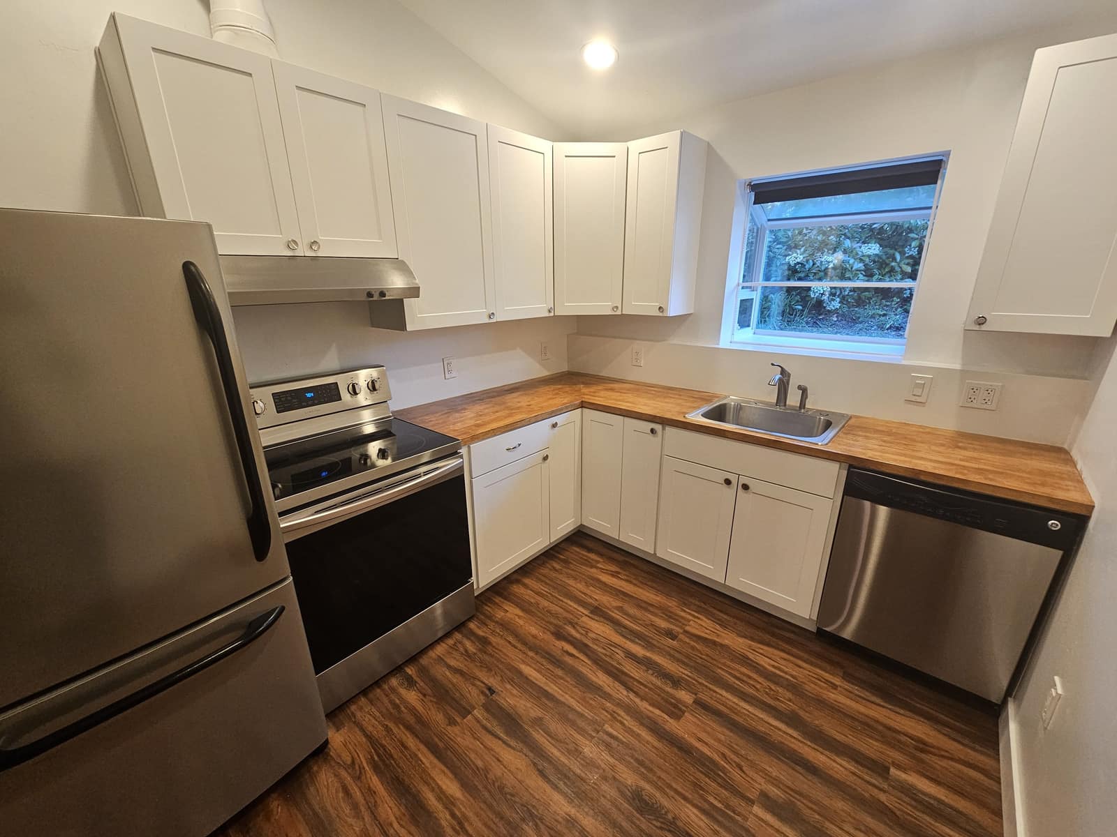 Kitchen in The Nest with white cabinets, wood counters, and a window onto the garden.