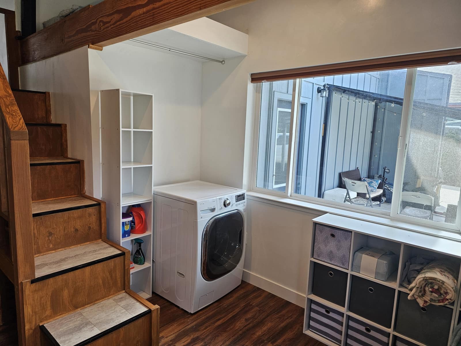 Laundry nook under the loft stairs, with a washer and storage cubes.