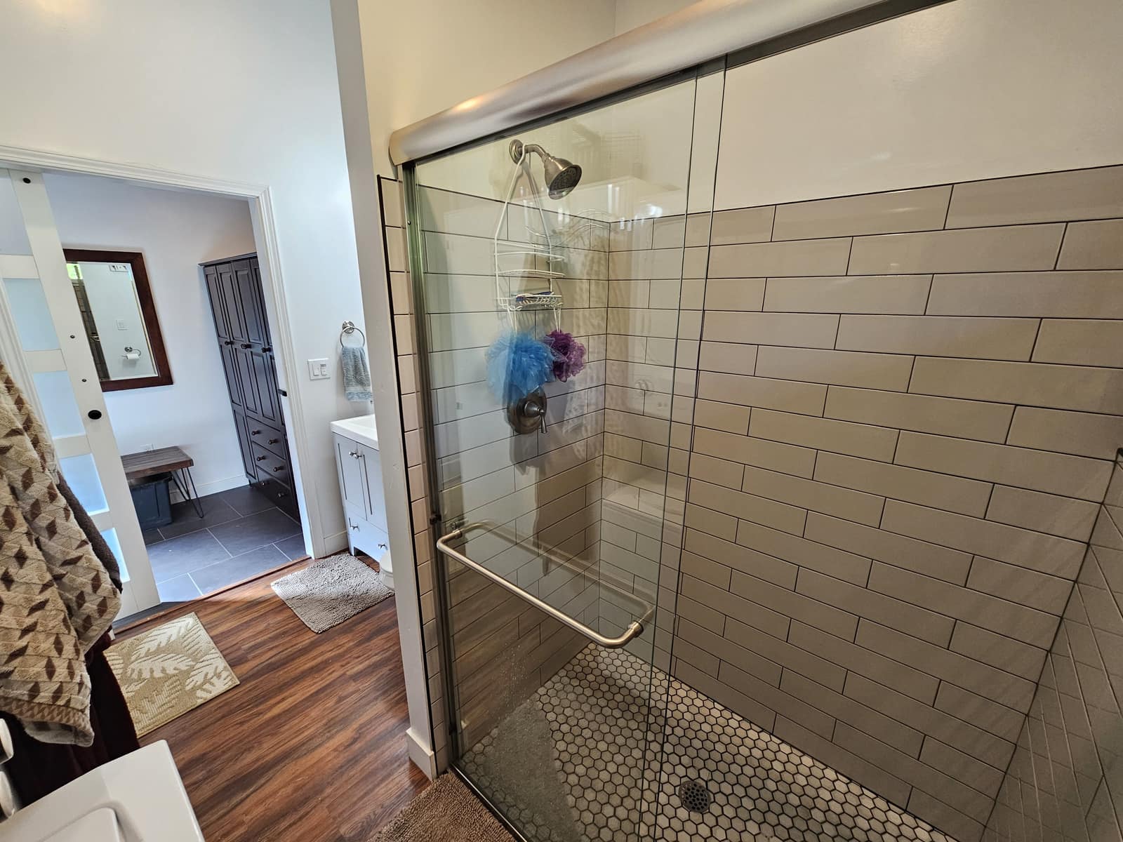 Walk-in shower in The Den with gray subway tile and a glass door.